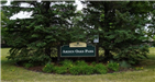 Arden Oaks Park Sign surrounded by pine trees and plants in the summertime