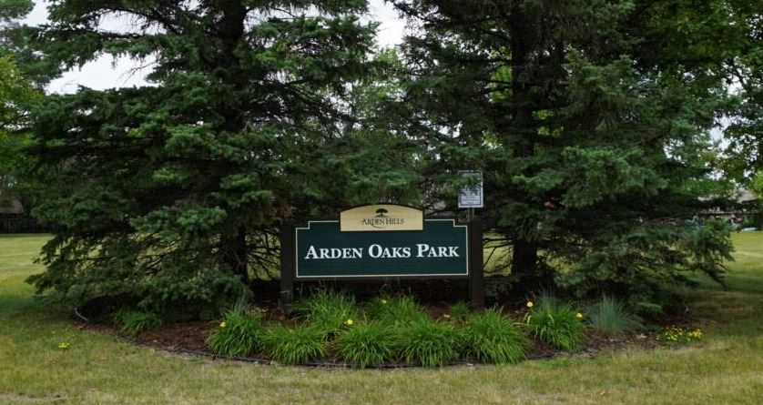 Arden Oaks Park Sign surrounded by pine trees and plants in the summertime